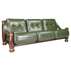 a green leather couch sitting on top of a wooden frame with two arms and legs