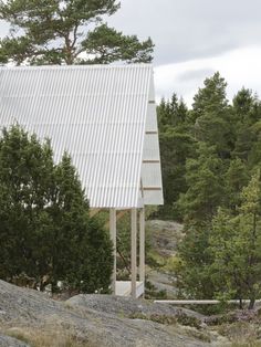 a tall white structure sitting in the middle of a forest next to rocks and trees