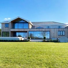 a large house sitting in the middle of a lush green field with lots of windows