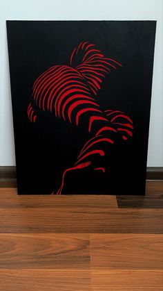 a black and red painting sitting on top of a wooden floor