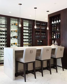 the interior of a modern home with wine cellars and bar stools in it