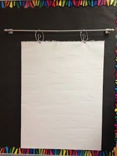 a white piece of paper hanging on a black wall with colorful streamers around it