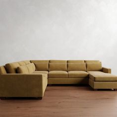 a large sectional couch sitting on top of a hard wood floor next to a white wall