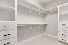 an empty walk in closet with white cabinets