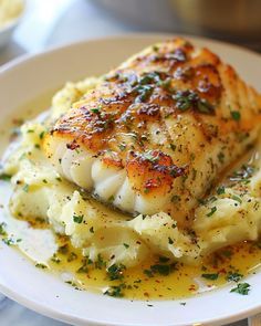 a white plate topped with fish and potatoes