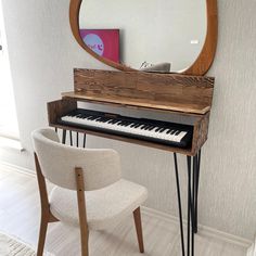 a piano sitting in front of a mirror on top of a wooden desk next to a chair