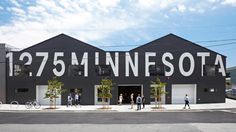 people walking on the sidewalk in front of a black building with white lettering that reads 75 minutes