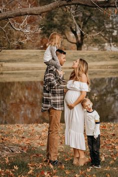 a woman and two children standing in front of a tree