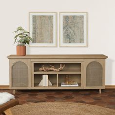 a living room scene with focus on the entertainment center and two framed pictures above it