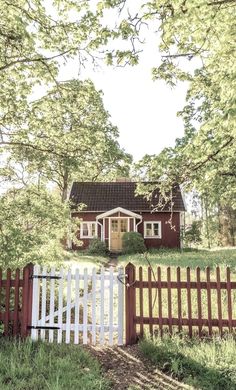 a white picket fence in front of a red house