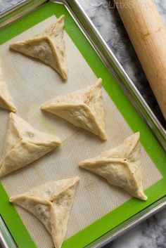 four dumplings on a baking sheet with a rolling pin