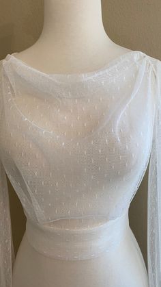 a white dress on a mannequin with sheer sleeves and beaded trims