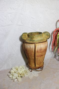 a vase sitting on top of a table next to a flower pot and lace doily