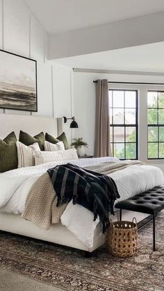 a large white bed sitting in a bedroom next to a window