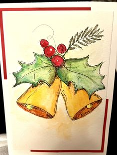 a card with two bells and holly leaves on it, sitting on top of a table