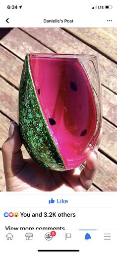 a hand holding a wine glass with green and pink designs