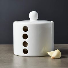 a white object with holes in it sitting on a table next to a slice of apple