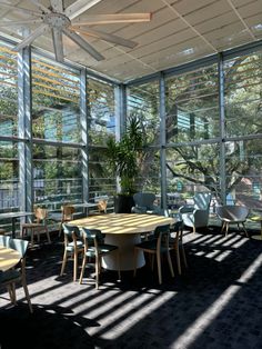 the sun shines through windows in an empty room with tables and chairs around them