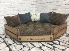 the dog bed is made out of wood and has four pillows on top of it