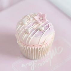 a pink cupcake with white frosting and flowers on it's icing