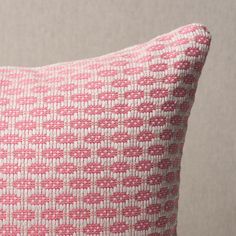 a pink and white pillow sitting on top of a table