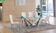 a glass dining table with white chairs and a rug on the floor in front of it