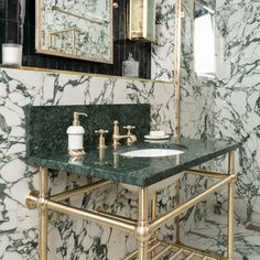 a bathroom with green marble counter top and gold faucet, mirror above the sink