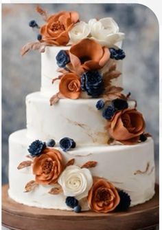 a three tiered white cake with orange and blue flowers