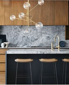 a kitchen with marble counter tops and stools next to an island in the middle