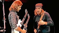 two young men playing guitars on stage with one looking at the other's face