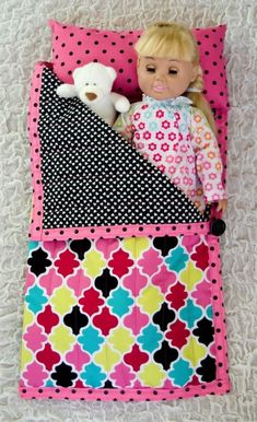 a doll laying on top of a pink and black blanket