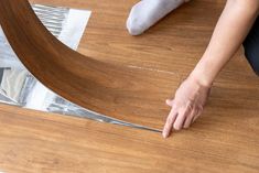 a person laying on top of a wooden floor next to a piece of wood with metal tape