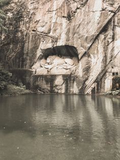 a large body of water next to a rocky cliff with an animal sleeping on it's side