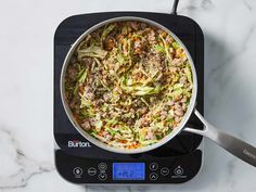 a pan filled with meat and vegetables on top of a digital scale next to a spatula