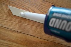 a bottle of glue sitting on top of a wooden floor