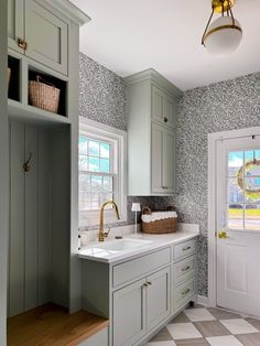 a kitchen with green cabinets and white counter tops next to a sink in front of a window