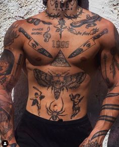 a man with lots of tattoos on his body and chest is standing in front of a wall