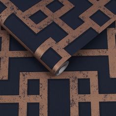 a roll of tape sitting on top of a black and gold patterned wallpaper design