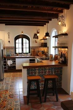 a kitchen with two stools next to an island