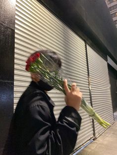 a person holding flowers in front of a closed door on the side of a building