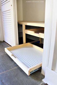 an open drawer on the floor in front of a white door with black polka dots