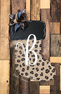 a wooden sign with a leopard print boot and the letter b on it's side