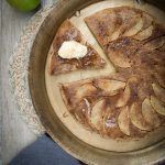 an apple pie with slices cut out in a pan on a table next to some apples