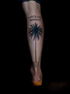 a person's leg with a palm tree and the words catch the moment on it