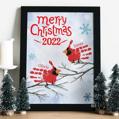 two red birds sitting on top of a tree next to snow covered trees and christmas decorations