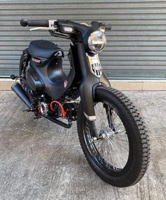 a black motorcycle parked in front of a garage door with no one on the bike