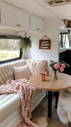 a couch and table in a small living area with white walls, wood flooring and windows