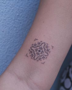 a woman's arm with a small tattoo design on the left side of her arm