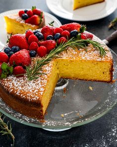 a cake on a plate with berries and powdered sugar around the edges, ready to be eaten