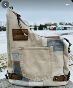 a purse sitting on top of a wooden bench in the snow with its pocket open